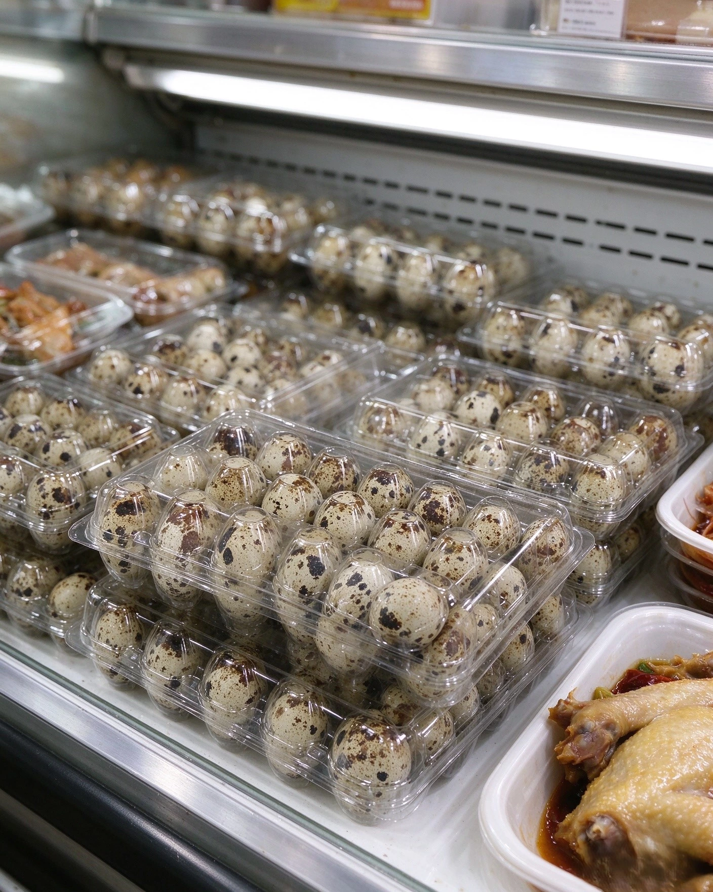 PET tri-fold quail egg boxes displayed on supermarket fresh shelf, filled with fresh quail eggs